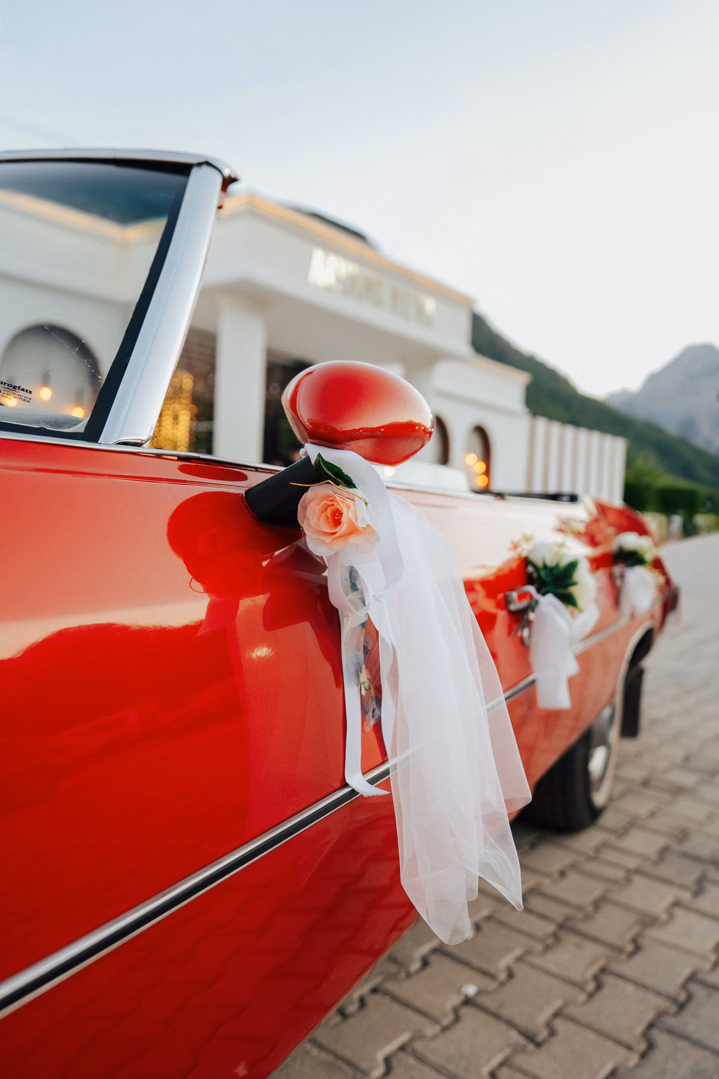A wedding car decorated with ribbon and flowers, parked in a street.